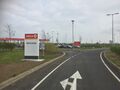 A road sign positioned behind a Circle K sign.